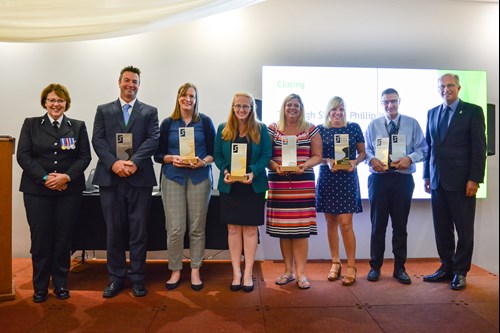 All in a row standing and smiling with their awards